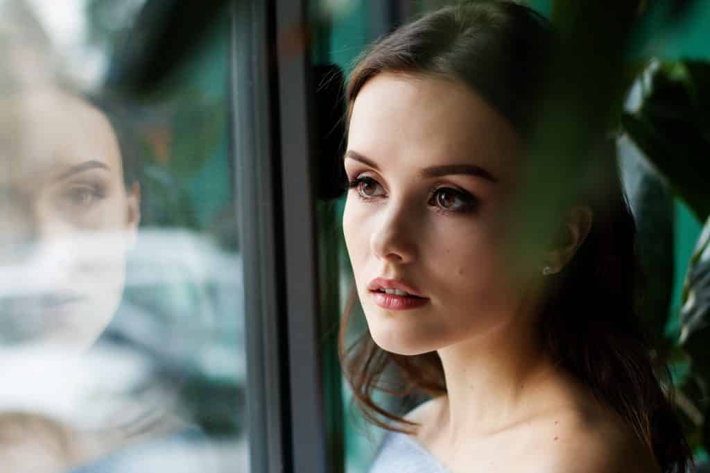 A woman posing beside a glass window