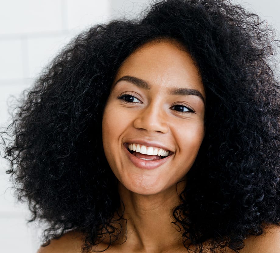 Curly haired woman smiling while looking to the side