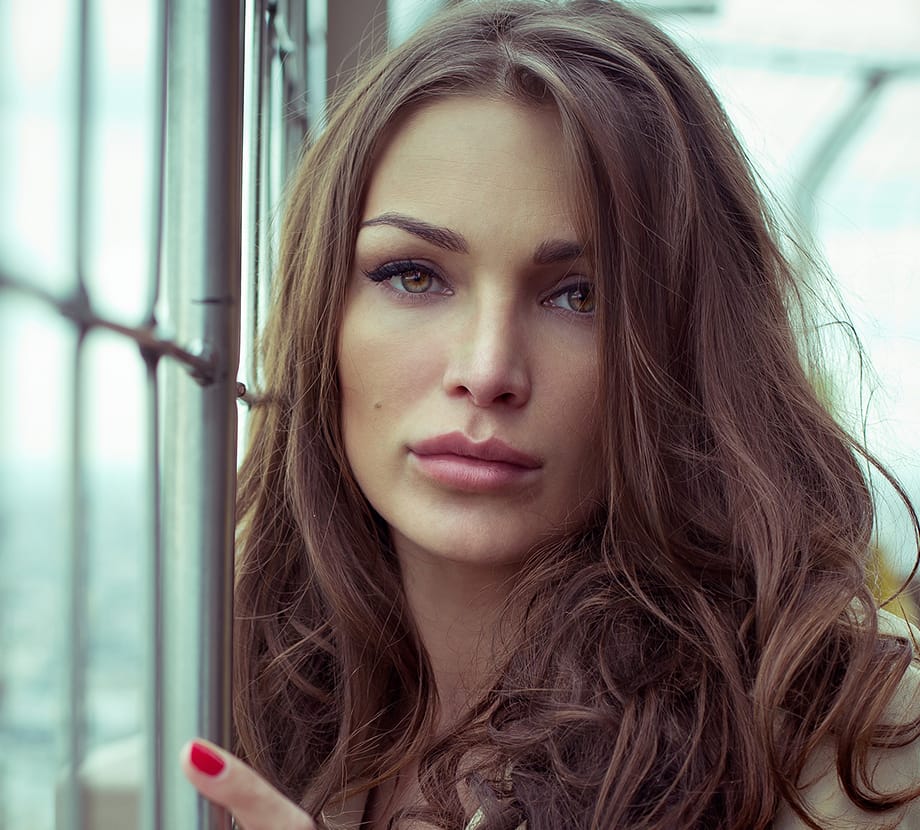 Woman leaning up against fence while looking at camera