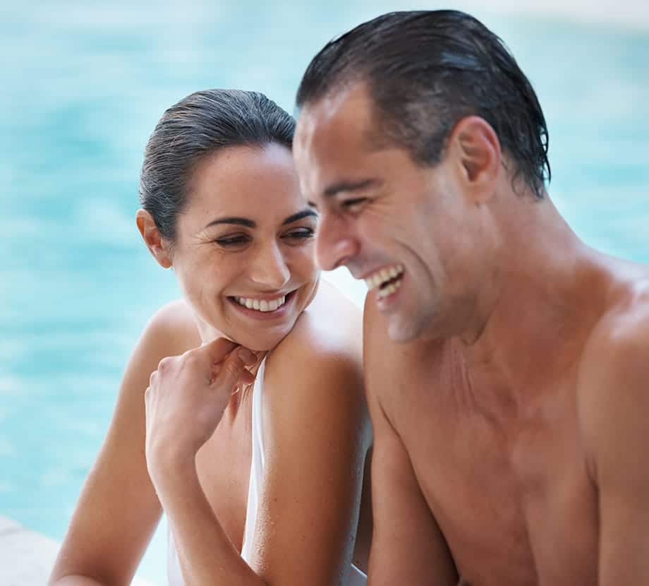 Woman and man smiling while in a pool