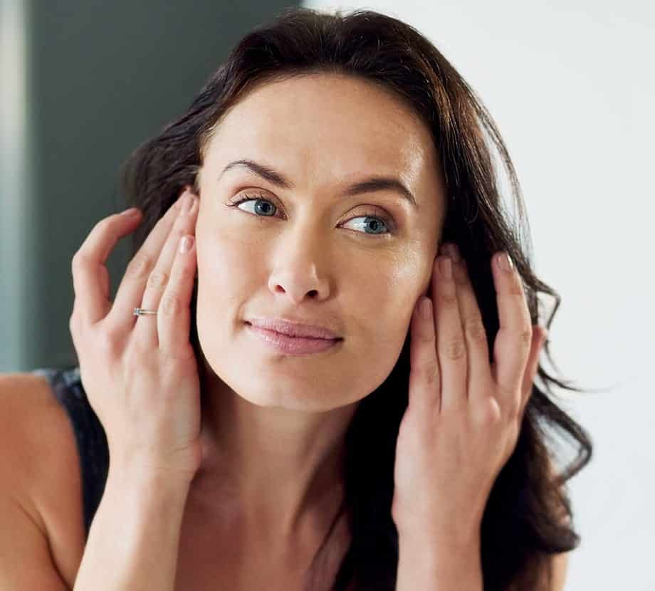 Woman looking at her skin in the mirror