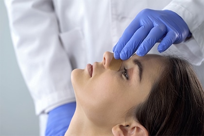 Doctor examining patient nose after rhinoplasty surgery