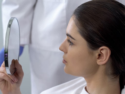 woman looking at face after rhinoplasty