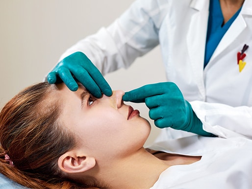 Lady with plaster on nose while doctor examining patients face after plastic surgery