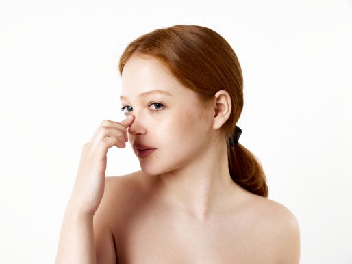 Concerned woman touching her nose considering saddle nose repair surgery.